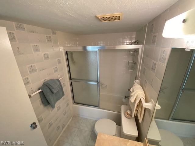 bathroom with shower / bath combination with glass door, tile patterned flooring, and toilet