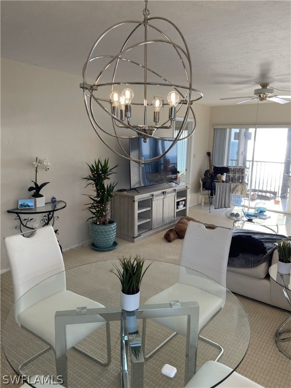 carpeted living room with ceiling fan with notable chandelier