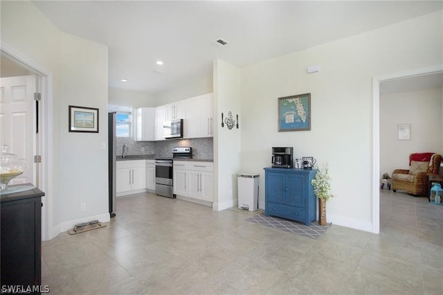 kitchen with white cabinets, backsplash, stainless steel appliances, and sink