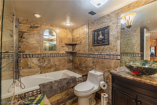 bathroom with vanity, tile patterned floors, tile walls, toilet, and a textured ceiling