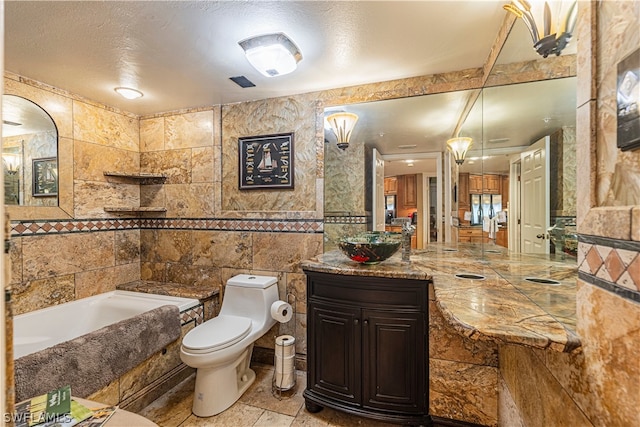 bathroom featuring a textured ceiling, toilet, vanity, tile walls, and tile patterned floors