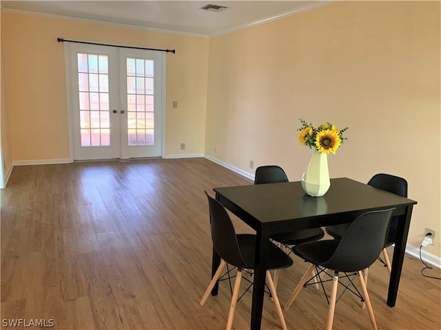 dining room featuring ornamental molding, hardwood / wood-style flooring, and french doors