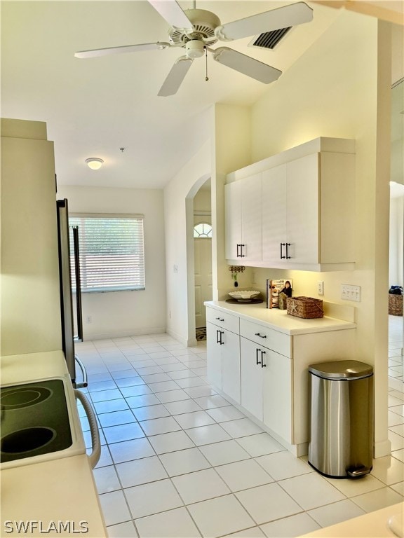 kitchen featuring light tile patterned flooring, stainless steel fridge, white cabinets, ceiling fan, and stove