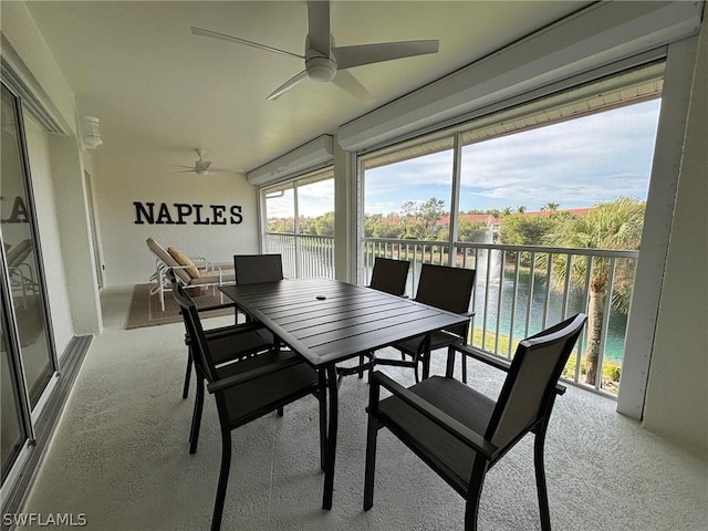 sunroom / solarium featuring a water view and ceiling fan