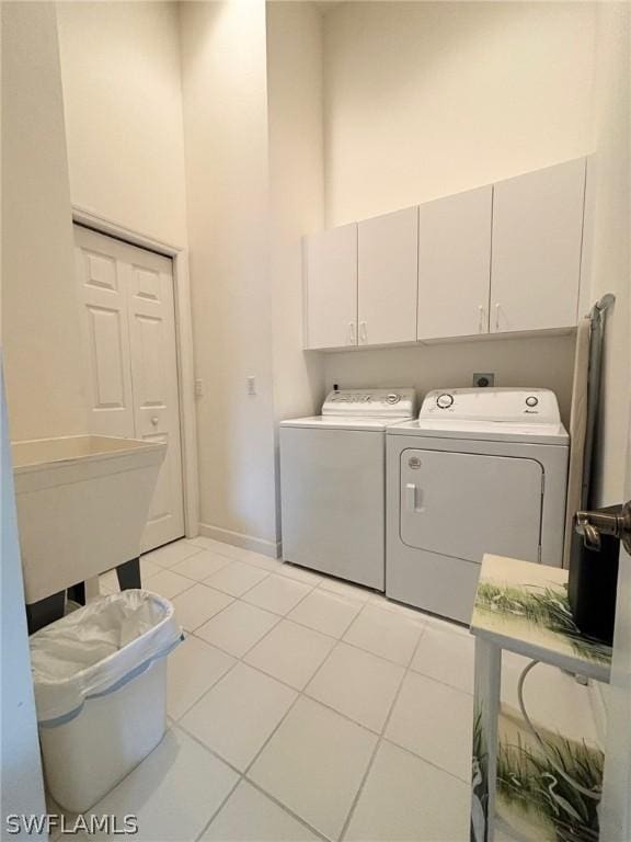 laundry room featuring independent washer and dryer, cabinets, and light tile patterned floors