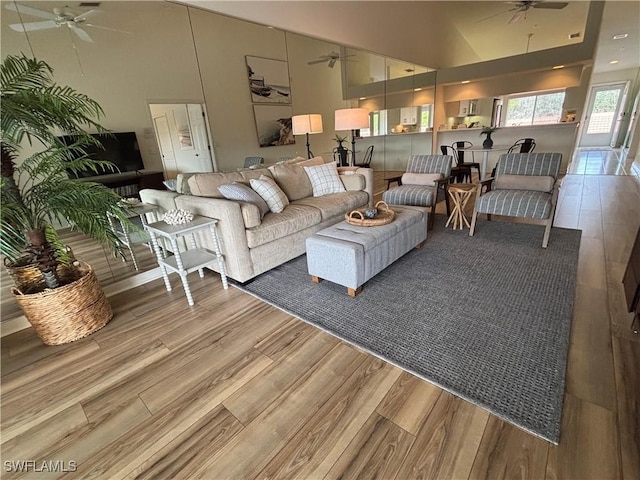 living room featuring hardwood / wood-style flooring, a towering ceiling, and ceiling fan