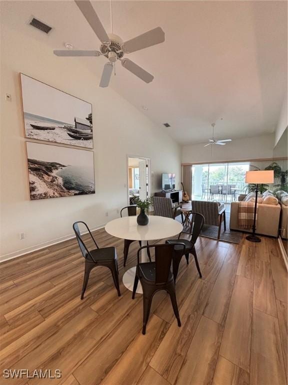 dining space with ceiling fan, high vaulted ceiling, and light hardwood / wood-style floors