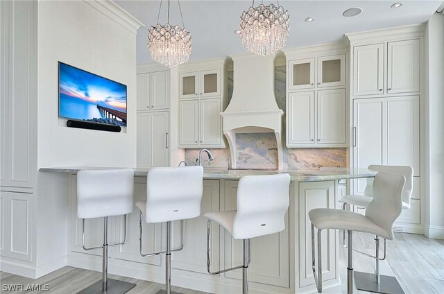 kitchen with pendant lighting, tasteful backsplash, light stone counters, and a notable chandelier