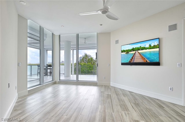 empty room featuring ceiling fan, a water view, and light hardwood / wood-style floors