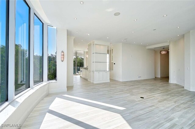 unfurnished room with light wood-type flooring and a chandelier