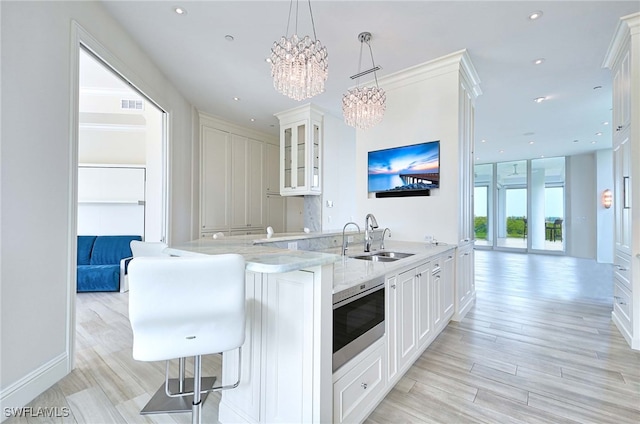 kitchen with stainless steel microwave, sink, decorative light fixtures, white cabinetry, and kitchen peninsula