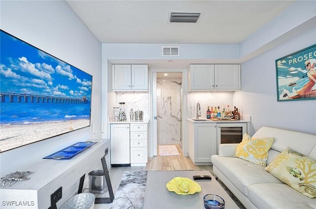 living room with light hardwood / wood-style floors, wine cooler, and sink