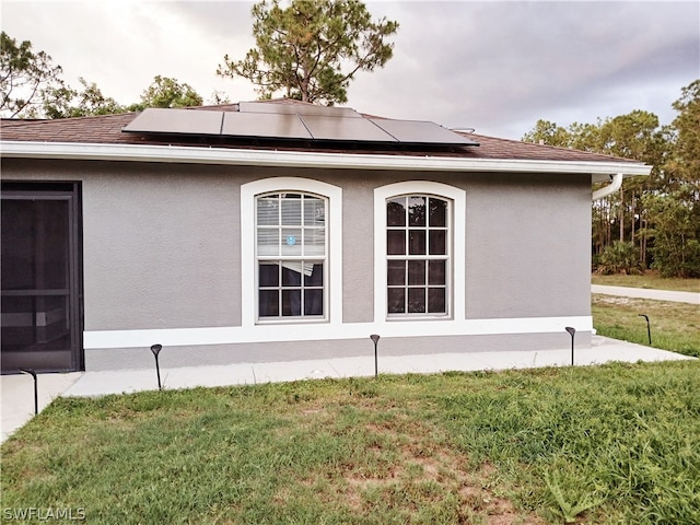 view of property exterior with solar panels and a yard