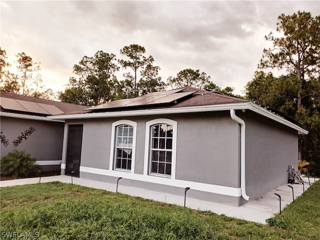 view of property exterior with solar panels and a lawn