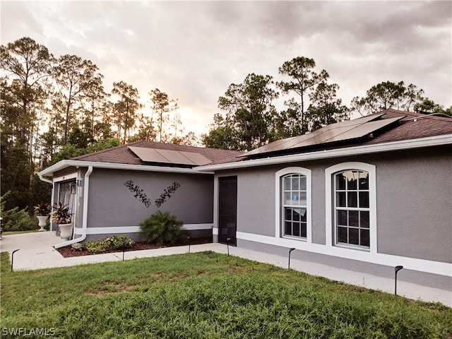 view of front of home featuring solar panels and a front yard