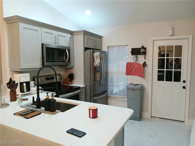 kitchen with kitchen peninsula, appliances with stainless steel finishes, lofted ceiling, and gray cabinetry