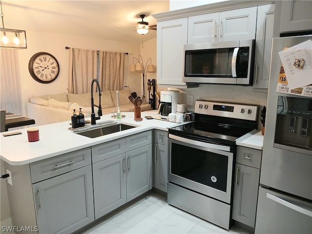 kitchen with gray cabinetry, sink, kitchen peninsula, decorative light fixtures, and appliances with stainless steel finishes