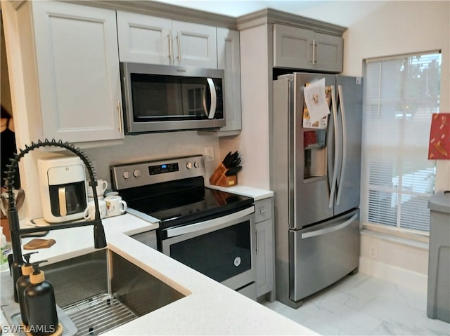 kitchen with gray cabinets, appliances with stainless steel finishes, and vaulted ceiling