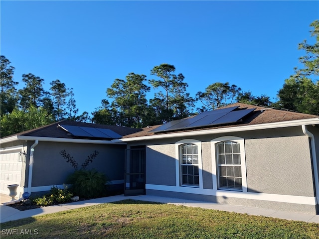 single story home with a garage and solar panels