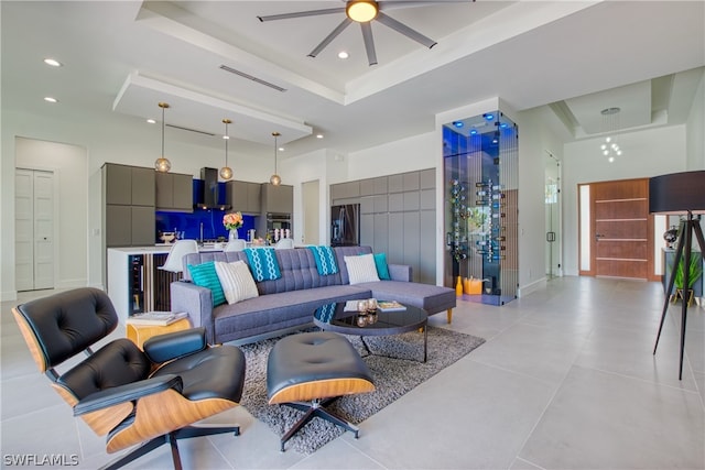 tiled living room with ceiling fan and a raised ceiling