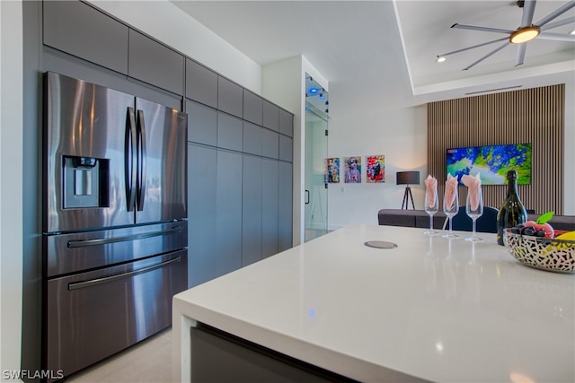 kitchen featuring a tray ceiling, stainless steel fridge with ice dispenser, ceiling fan, and gray cabinetry