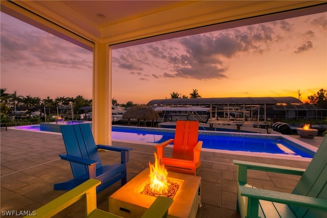 pool at dusk featuring a fire pit and a patio