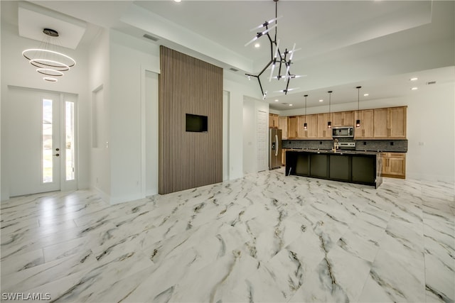 kitchen featuring tasteful backsplash, stainless steel appliances, pendant lighting, a kitchen island with sink, and light tile patterned flooring