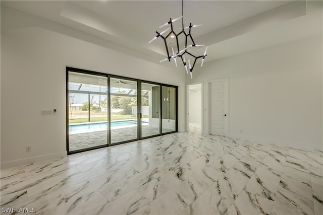 tiled empty room featuring a tray ceiling and an inviting chandelier