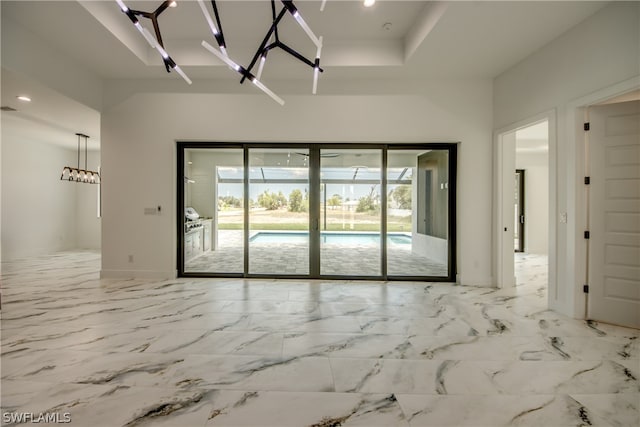 unfurnished room with a chandelier, a raised ceiling, and tile patterned floors