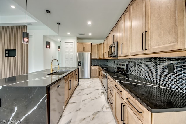 kitchen with light tile patterned flooring, hanging light fixtures, appliances with stainless steel finishes, and an island with sink