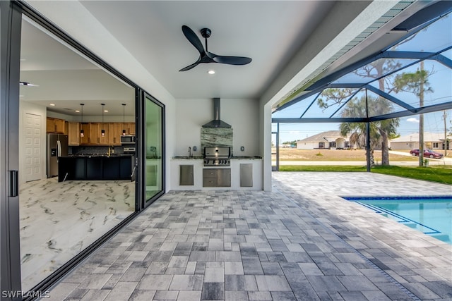 view of patio with area for grilling, ceiling fan, glass enclosure, and a grill