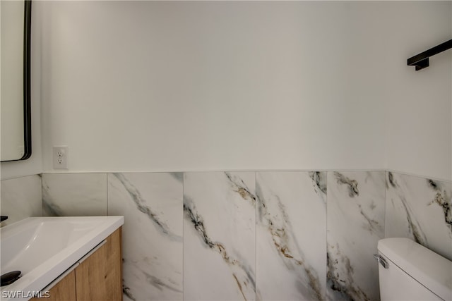 bathroom with vanity, tile walls, and toilet