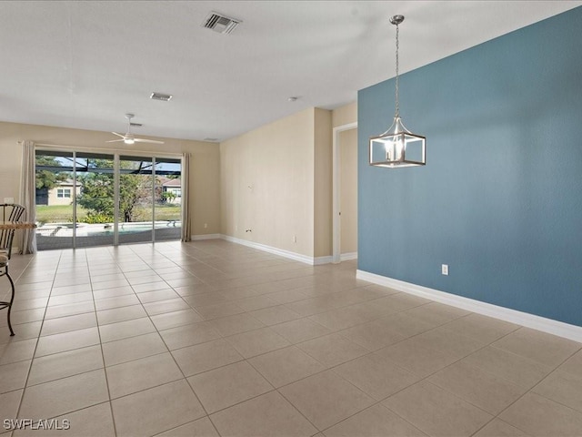 tiled empty room with ceiling fan with notable chandelier