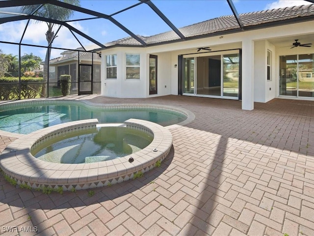 view of pool with a patio area, glass enclosure, ceiling fan, and an in ground hot tub