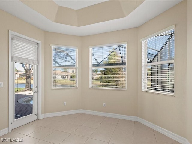 tiled spare room featuring a tray ceiling