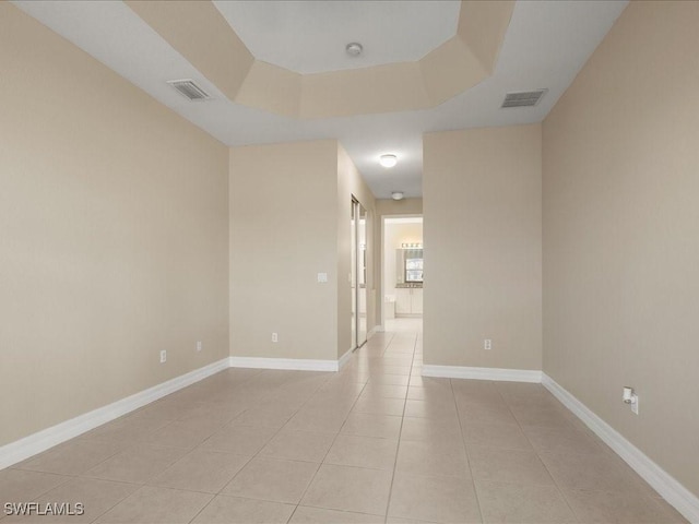 unfurnished room with light tile patterned floors and a raised ceiling