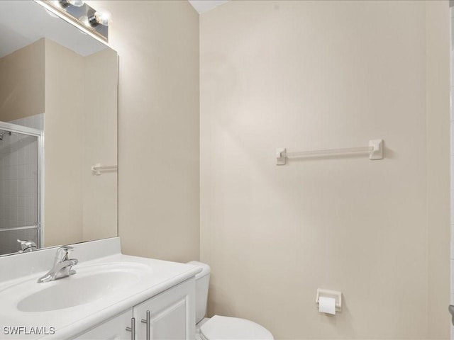 bathroom featuring vanity, a shower with door, and toilet