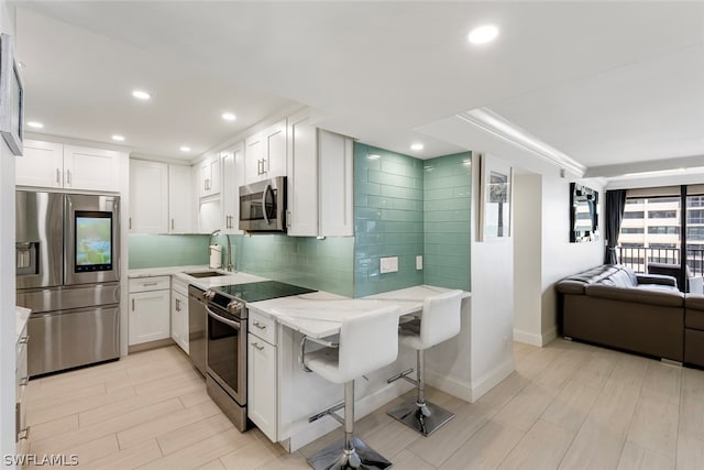 kitchen with stainless steel appliances, sink, decorative backsplash, and white cabinets