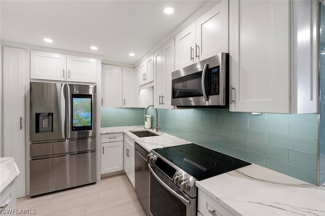 kitchen featuring light stone counters, stainless steel appliances, sink, and white cabinets