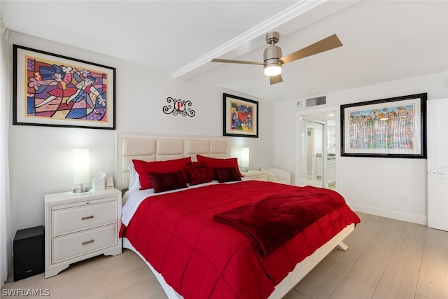 bedroom with beamed ceiling, ensuite bathroom, ceiling fan, and light hardwood / wood-style flooring