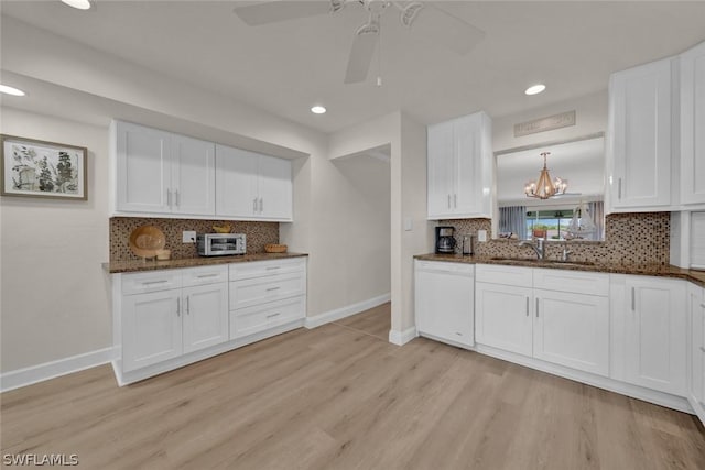 kitchen featuring white cabinetry, white dishwasher, a sink, light wood-type flooring, and baseboards