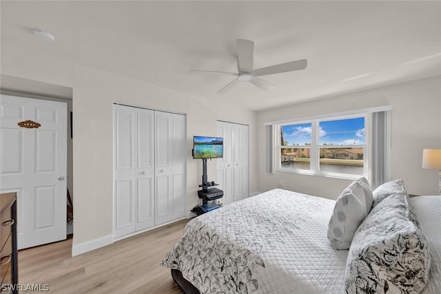 bedroom with multiple closets, baseboards, ceiling fan, and light wood finished floors