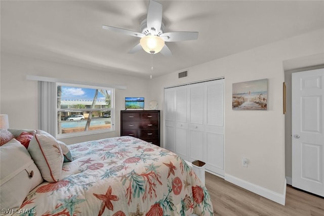 bedroom featuring light wood finished floors, a closet, visible vents, a ceiling fan, and baseboards