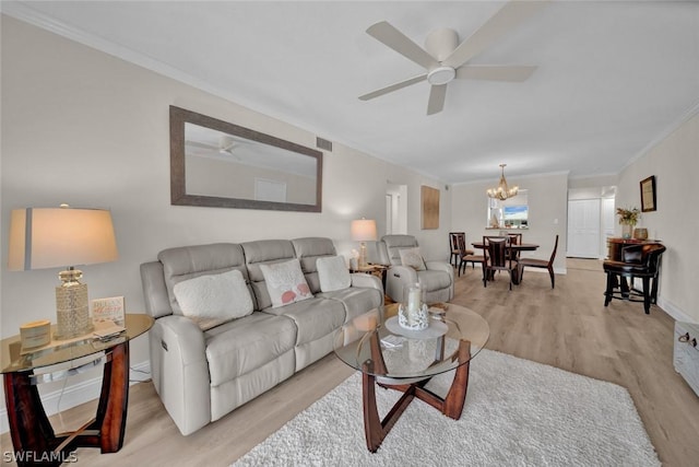 living area with visible vents, baseboards, ornamental molding, light wood-style floors, and ceiling fan with notable chandelier