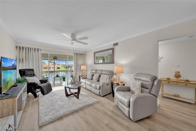 living area with visible vents, ceiling fan, wood finished floors, a water view, and crown molding