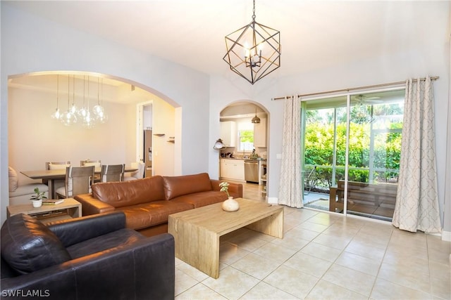 living room with a chandelier, light tile patterned floors, arched walkways, and baseboards