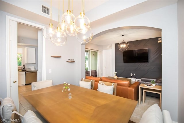dining room with a chandelier, arched walkways, and light tile patterned floors