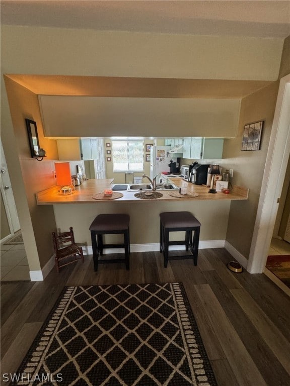 kitchen with a kitchen breakfast bar, kitchen peninsula, and dark wood-type flooring