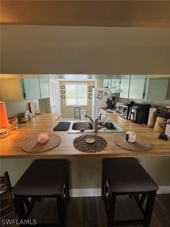 kitchen with a breakfast bar area, sink, white cabinetry, and dark hardwood / wood-style floors