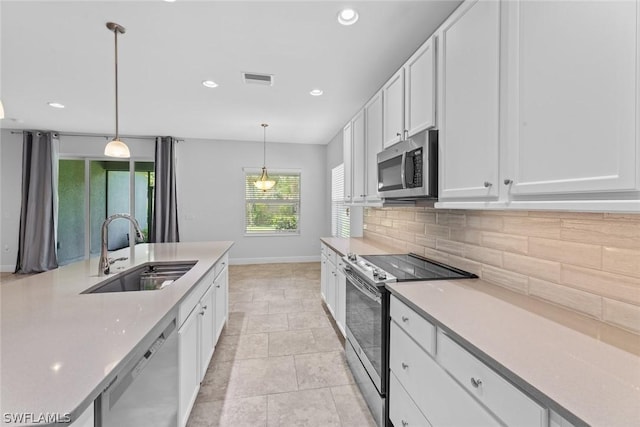 kitchen with appliances with stainless steel finishes, pendant lighting, white cabinetry, sink, and decorative backsplash